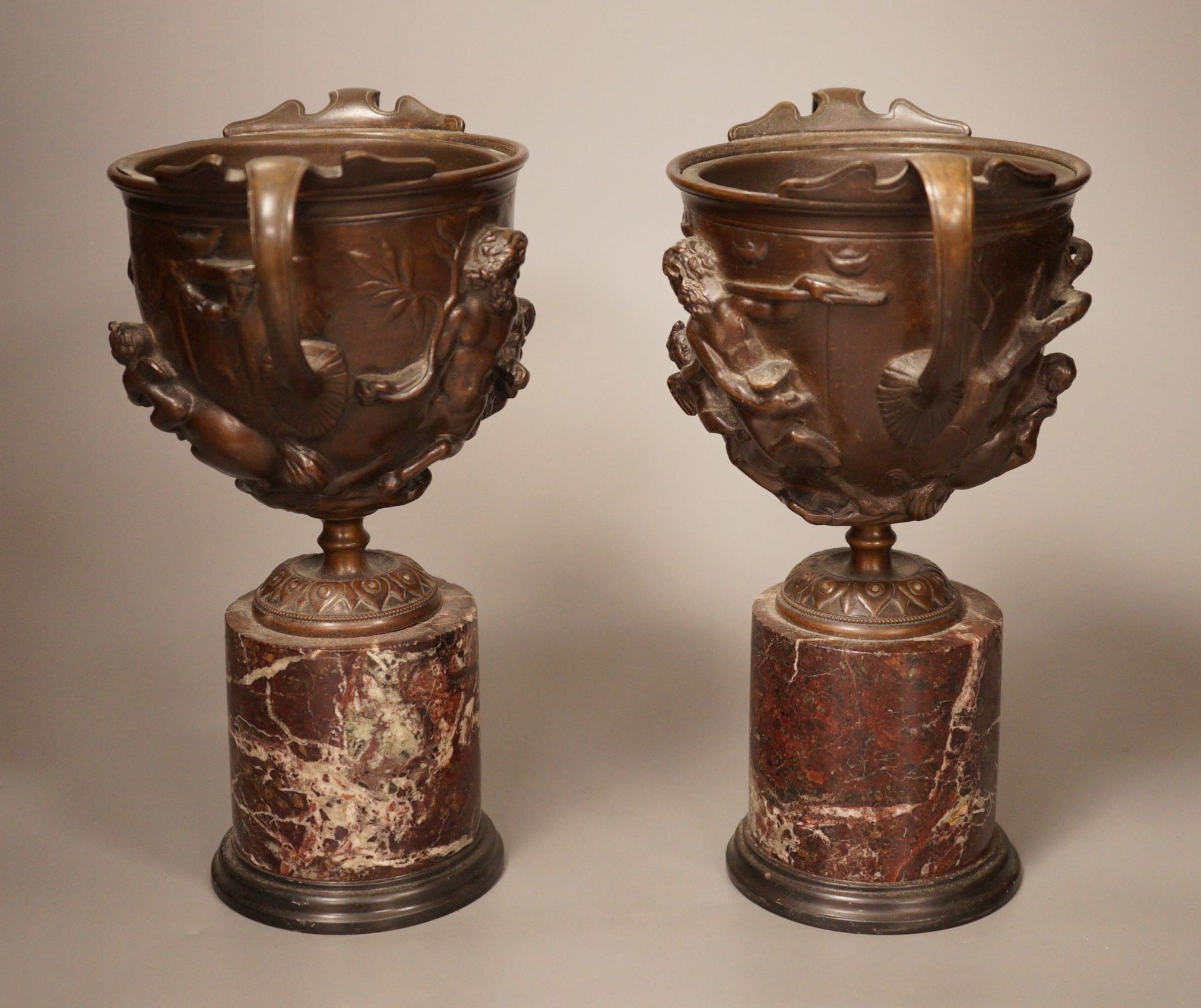 A pair of early 20th century twin handled bronze cups on marble plinth bases, 22cm